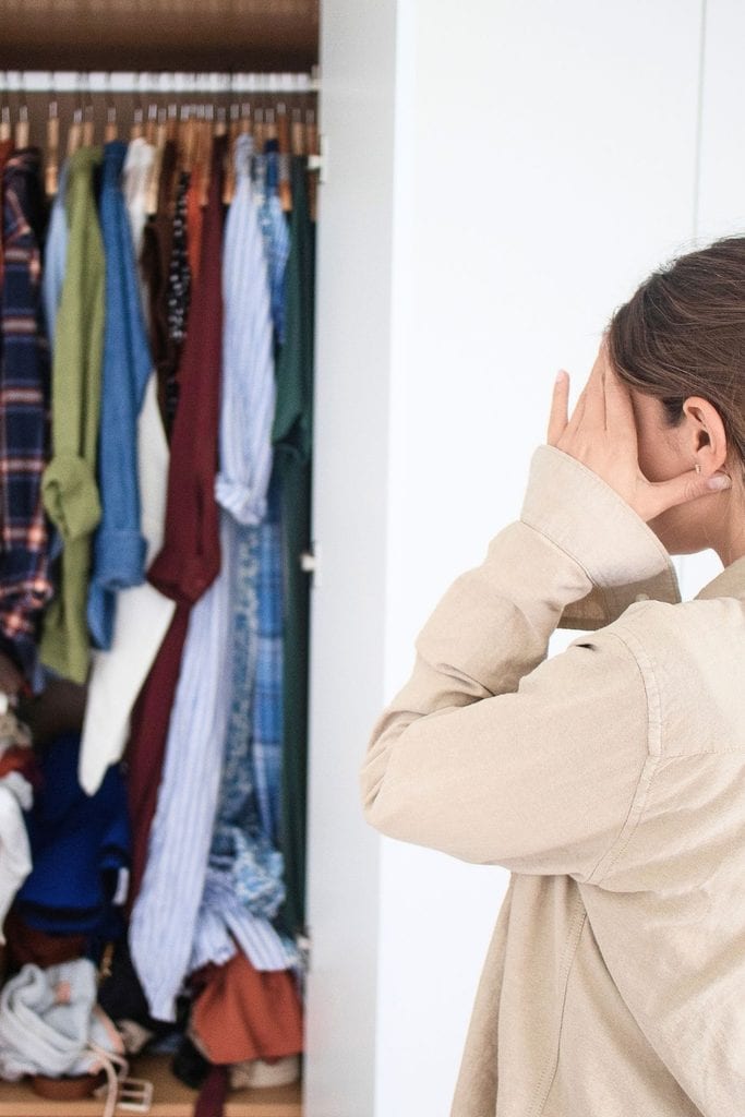 Woman overwhelmed by cluttered closet, seeking clarity and organization.