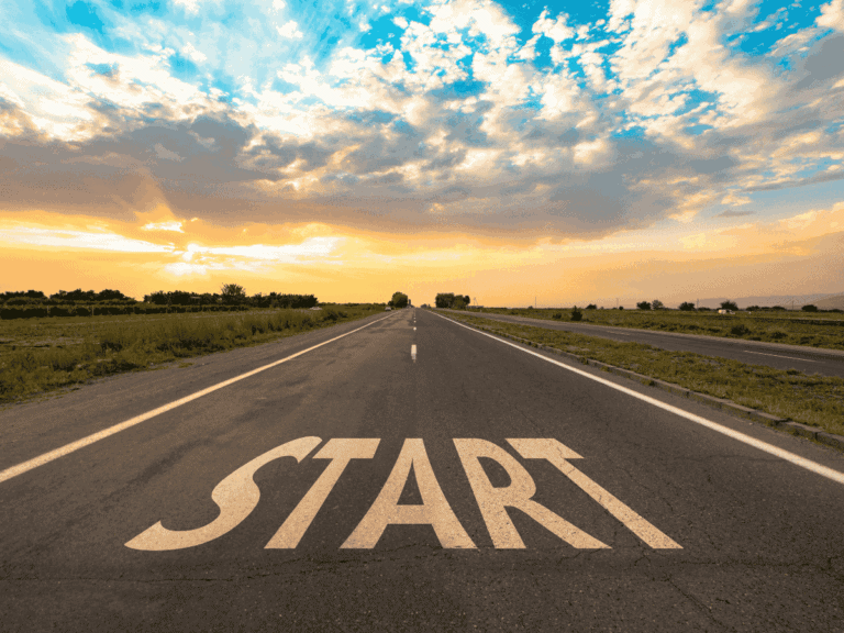 photo of colorful sunrise beyond a long road ahead with the word "start" at the beginning of the road