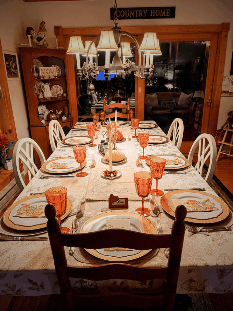Warm farmhouse dining table set for a fall family gathering with pumpkin decorations and fall-themed tableware.