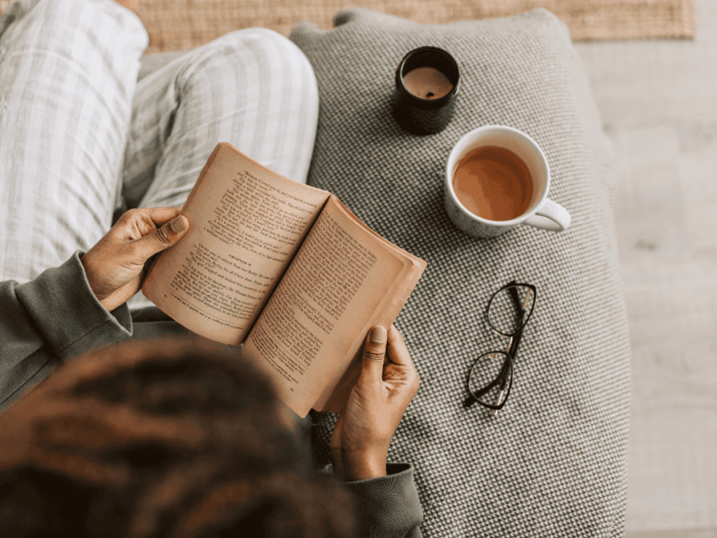 Relaxing moment of reading with coffee and glasses on a textured side table.