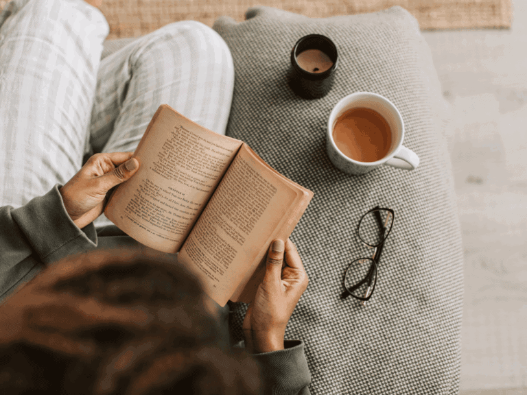 Relaxing moment of reading with coffee and glasses on a textured side table.
