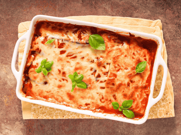 a photo from above of a hot pan of lasagna topped with melted cheese and green basil leaves adorning the dish.