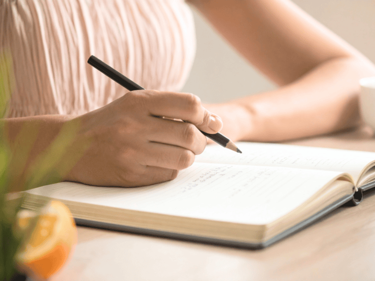 Person writing in a notebook, embracing new challenges with confidence.