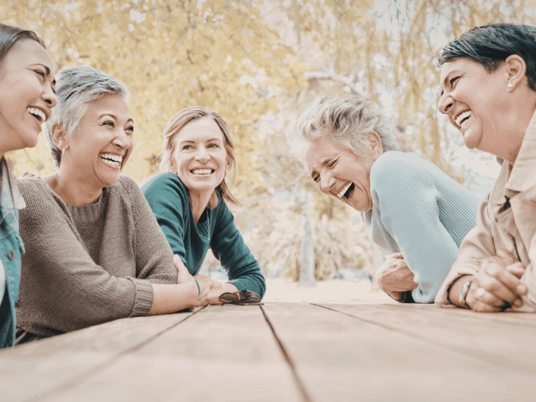 group of 4 women sitting at a picnic table and laughing and enjoying each other's company