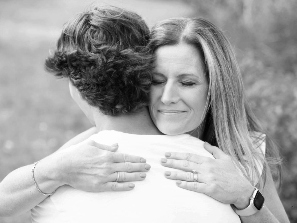 Mother and child sharing a heartfelt embrace outdoors in black and white.