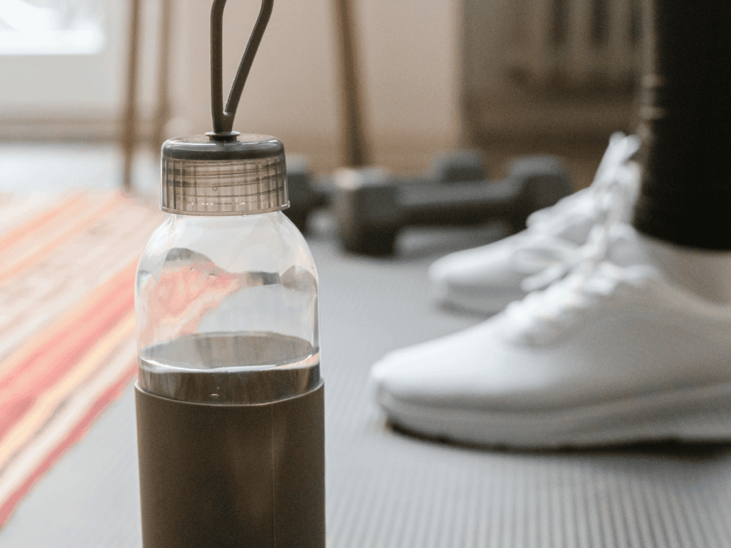 water bottle and sneakers on a workout mat at home