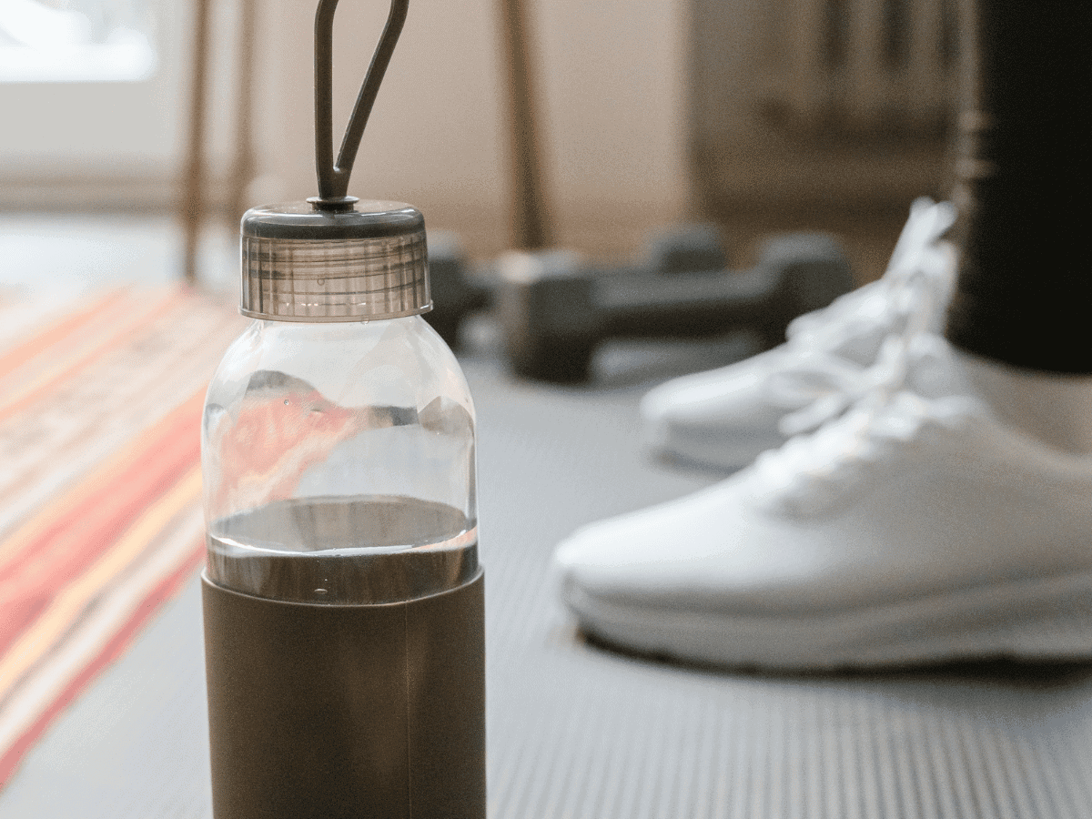 water bottle and sneakers on a workout mat at home