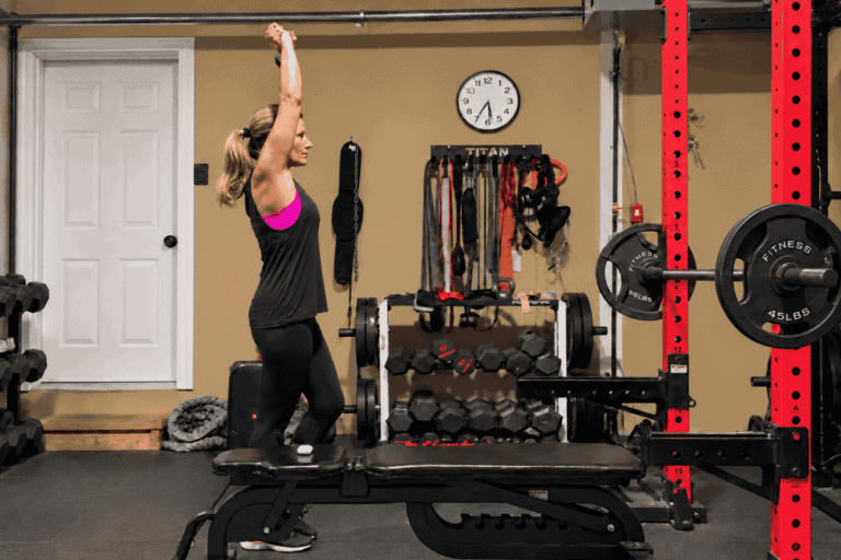 Woman stretching in home gym with weights and fitness equipment.